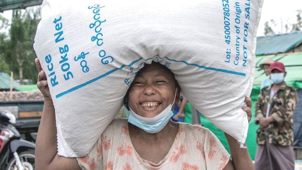 Woman in Myanmar carrying a sack of rice