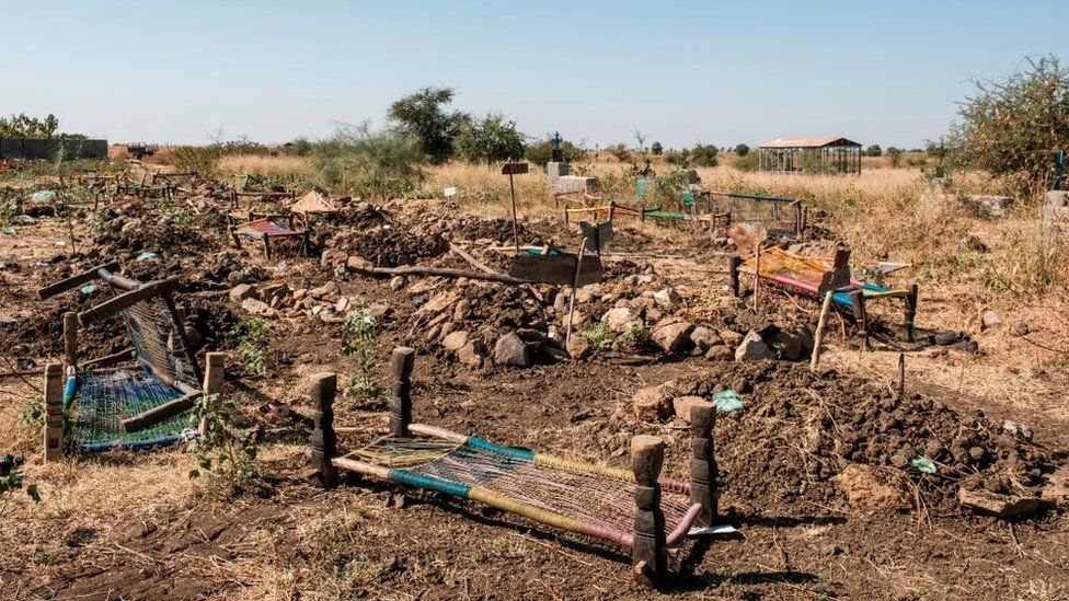 На этой фотографии, сделанной 21 ноября 2020 года, показаны брошенные кровати, используемые в качестве носилок для переноски тел, лежащих рядом с коллективными могилами на кладбище, жертв, которые предположительно были убиты в резне 9 ноября 2020 года в Май-Кадре, Эфиопия