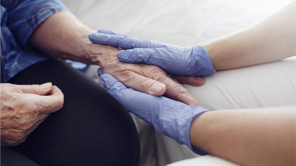 Nurse holds elderly woman's hand