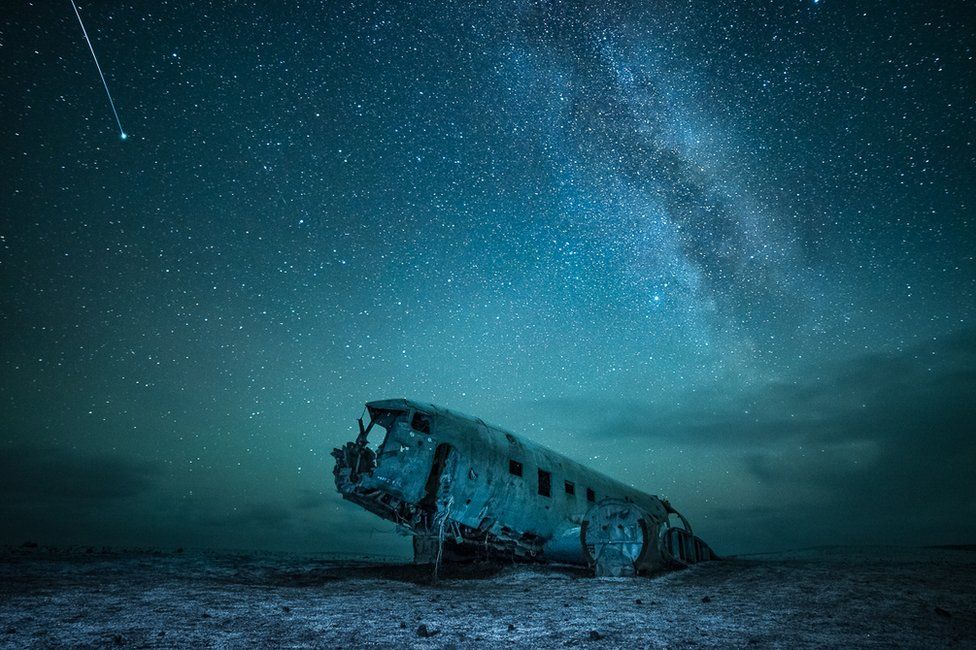 A starlit sky above an abandoned war plane