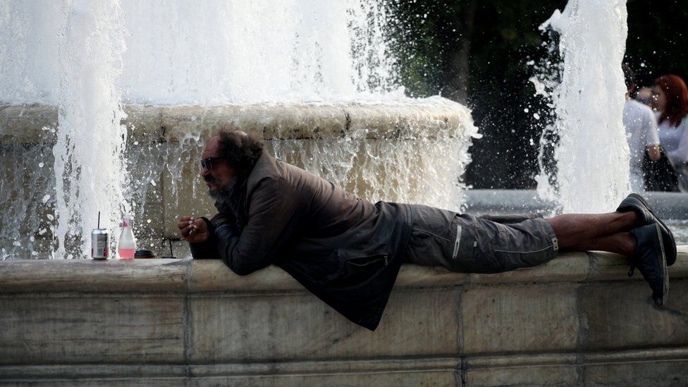 A man rests by the water fountain in Syntagma square in Athens, Greece, May 11, 2017