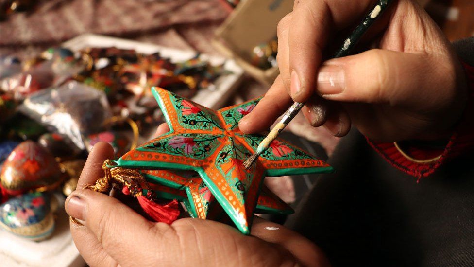 Kashmiri artisan giving finishing touch to a Christmas ornament in his workshop ahead of Christmas celebrations in Srinagar,Kashmir on December 13 , 2021.The artisans say that the Christmas items are made of paper-mache and are sent to local markets and also exported to the U.S, Italy and many other parts of the world.