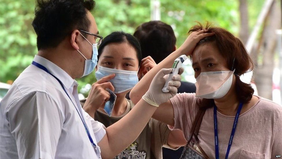 A hospital worker (L) checks the body heat of visitors at a gate of Samsung Medical Center in Seoul on (20 July 2015)