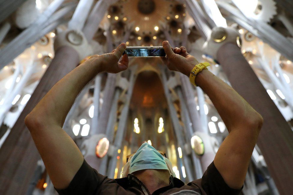 A man uses his phone as health workers, police officers and NGO staff members with their families visit the Sagrada Familia basilica as it reopens following the coronavirus disease (COVID-19) outbreak, in Barcelona, Spain, July 4, 2020