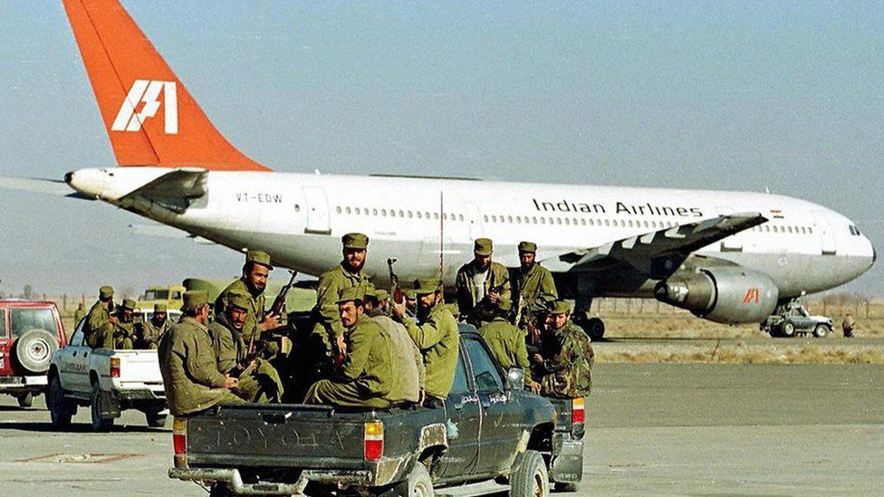 Taliban Islamic militia commandos ride in the rear of a truck towards an aircraft of Indian Airlines hijacked by Islamic Kashmiri militants