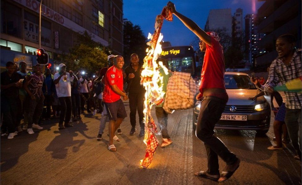 Zimbabweans living in South Africa celebrate by burning a banner with Robert Mugabe's image after President Robert Mugabe resigns, in Johannesburg, South Africa November 21, 2017.