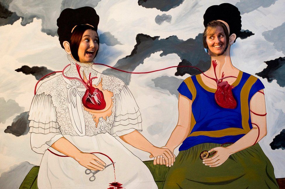 Two women pose in a Frida Kahlo cut out