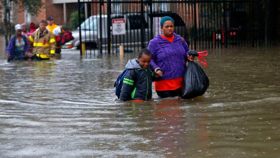 Residents wade through floodwaters from heavy rains in the Chateau Wein Apartments in Baton Rouge, La., Friday, Aug. 12, 2016