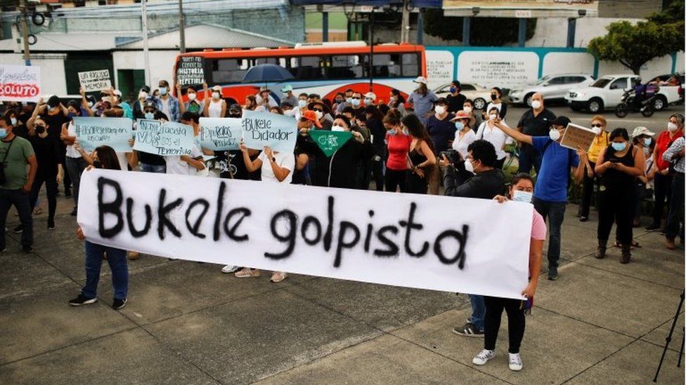 People hold a banner reading "Bukele coup plotter" as they protest against the removal of Supreme Court judges and the Attorney General by Salvadoran congress, in San Salvador, El Salvador, May 2, 2021.