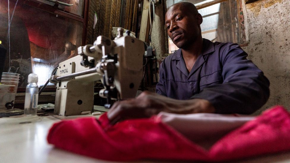 Mozambican Mateu Madjila sewing a garment in Alexandra township, Johannesburg, South Africa