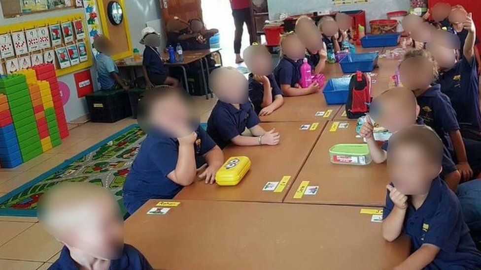White schoolchildren sit apart from black school children in the same classroom in South Africa