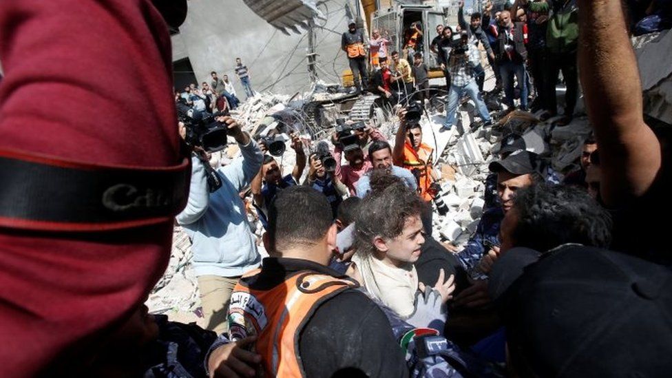 Rescuers carry Suzy Eshkuntana, 6, as they pull her from the rubble of a building at the site of Israeli air strikes