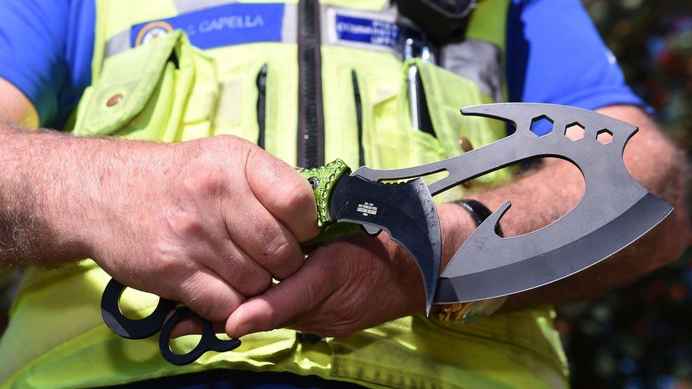 A police officer holds a zombie knife
