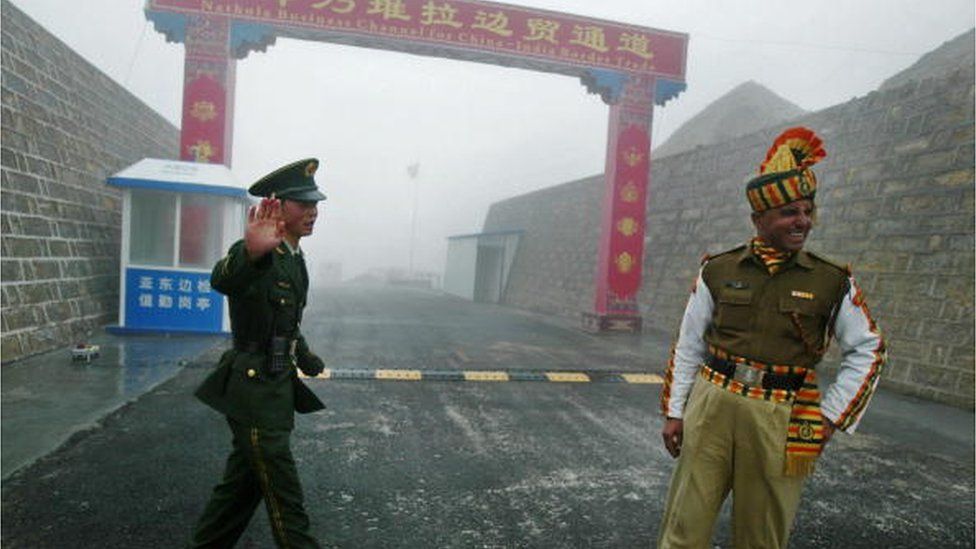 На этой фотографии, сделанной 10 июля 2008 г., китайский солдат (слева) и индийский солдат стоят на страже на китайской стороне древнего пограничного перехода Натху Ла между Индией и Китаем