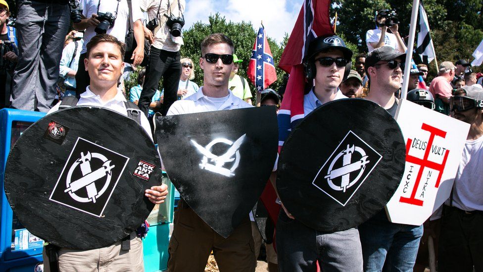 White nationalists hold shields with symbols on