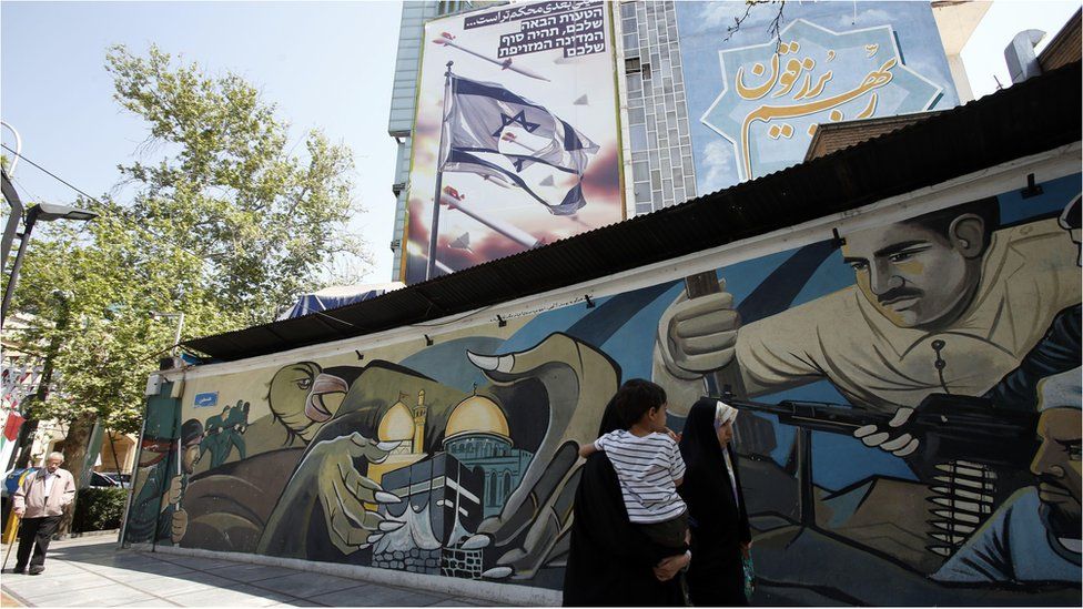 People walk below an anti-Israel billboard on a street in Tehran