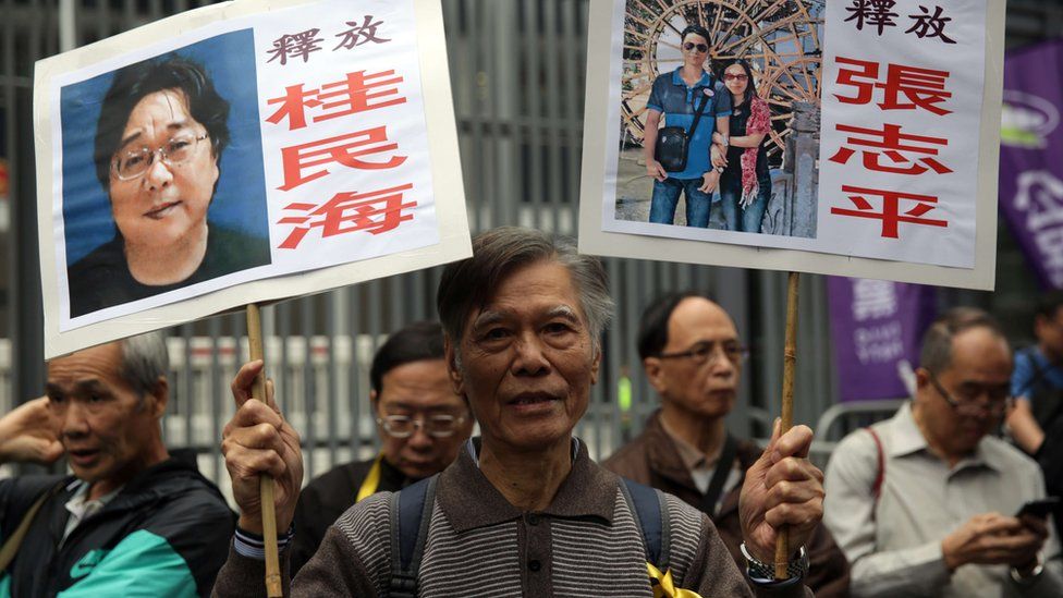 Protesters wave placards at a rally for five Hong Kong booksellers who disappeared