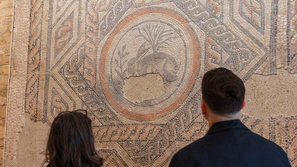 Image of two people looking at the original mosaic in Corinium Museum