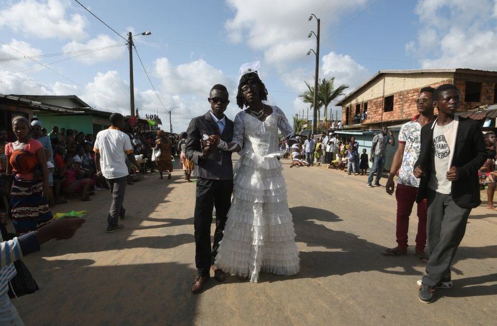 Men from the ethnic southeastern Aboure people, dressed up as a bride and groom, pose for a photograph during the 38th Edition of the POPO Carnival of Bonoua, 50 kms east of Abidjan, an annual festival held by the Aboure people on April 14, 2018.