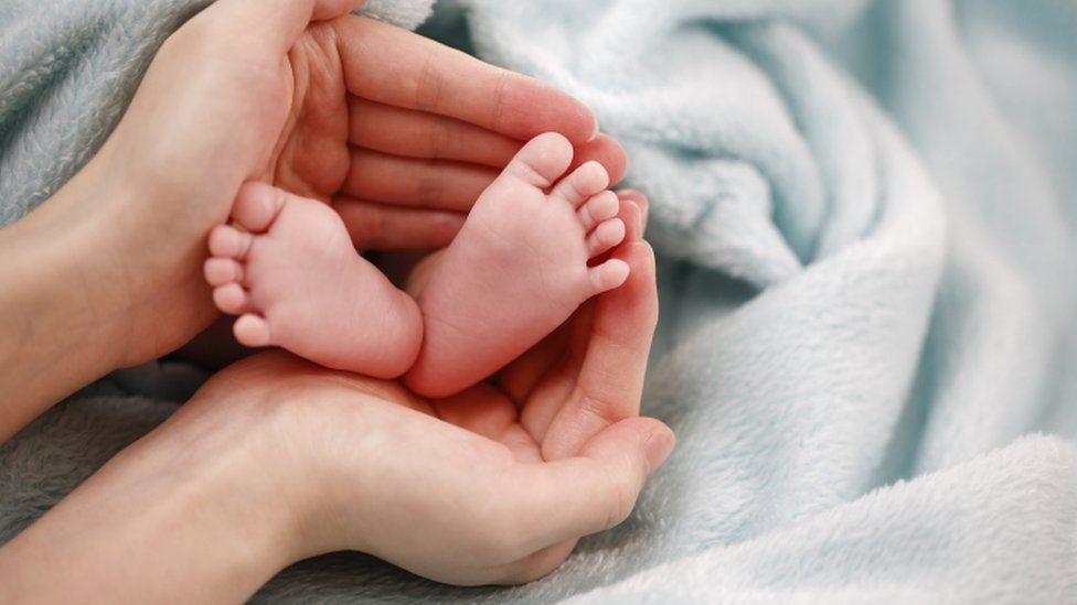 A woman's hands holding a baby's feet