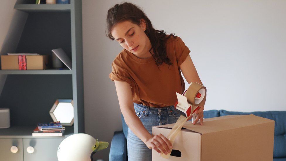 Изображение женщины, упаковывающей коробки для переезда