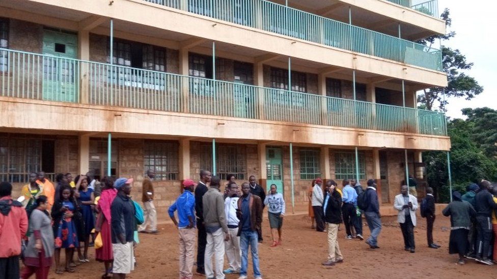 Parents and teachers gather near the scene of a stampede at the Kakamega primary school in Kakamega, Kenya