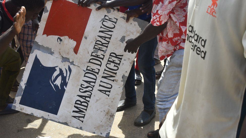 Протестующие держат табличку, взятую из посольства Франции в Ниамее, Нигер.