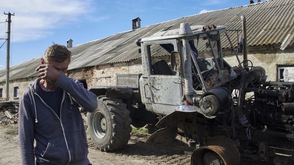 A man weeps near a tractor on the outskirts of Kyiv