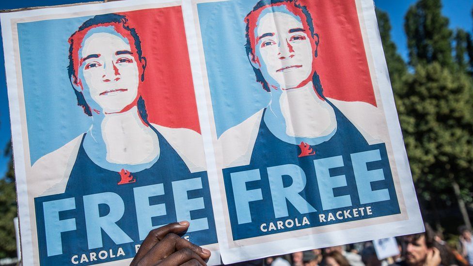 Supporters and activists hold signs reading "Free Carola Rackete"