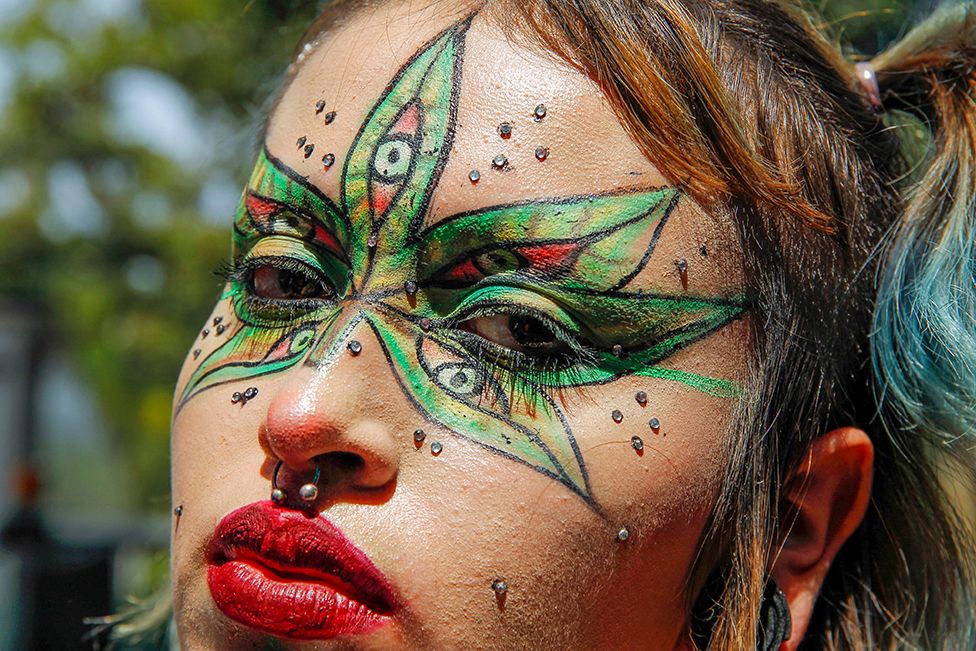 A woman with a marijuana leaf painted on her face poses for a picture during the Global Marijuana March demanding the decriminalisation of marijuana in Medellin, Antioquia province, Colombia, on 6 May 2023