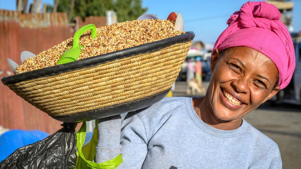 Woman carrying basket full of Kolo or roasted barley on her shoulder, Debre Berhan, Ethiopi