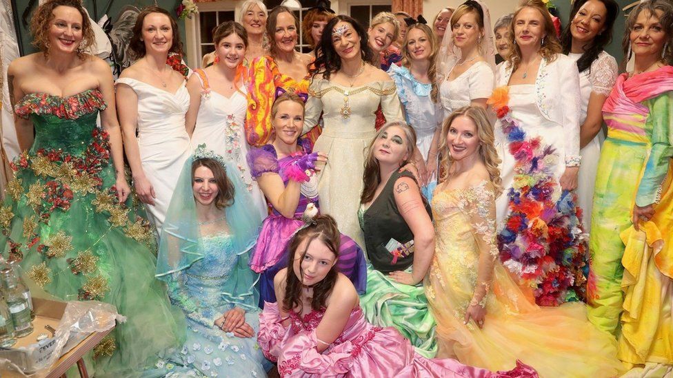 A group of volunteers wearing colourful upcycled dresses