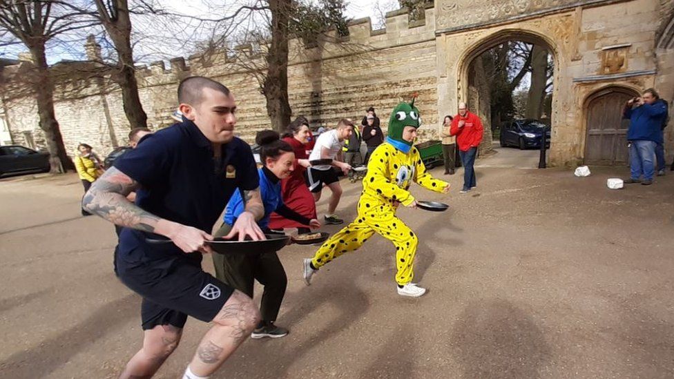 Participants in pancake race at Peterborough Cathedral