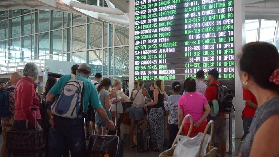 Passengers watch the information board at Bali"s International Airport