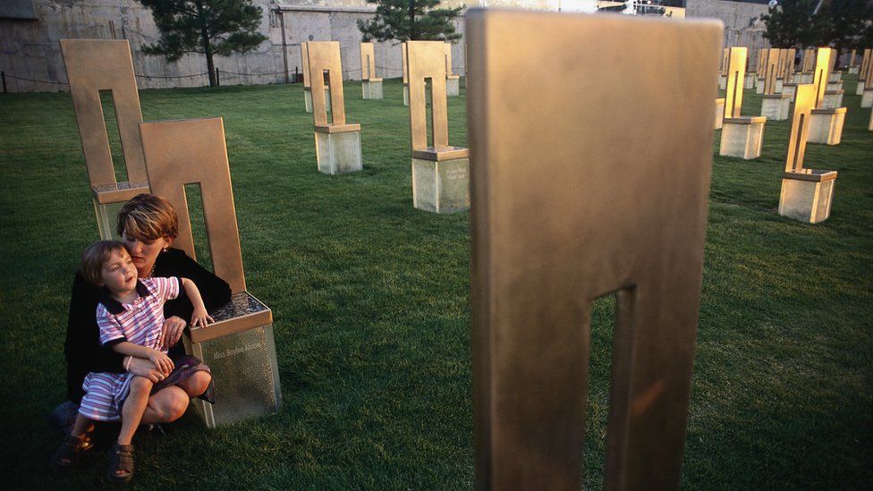 Aren Almon (in 2001) crouches with her daughter, Bella, at the memorial chair of her daughter, Baylee