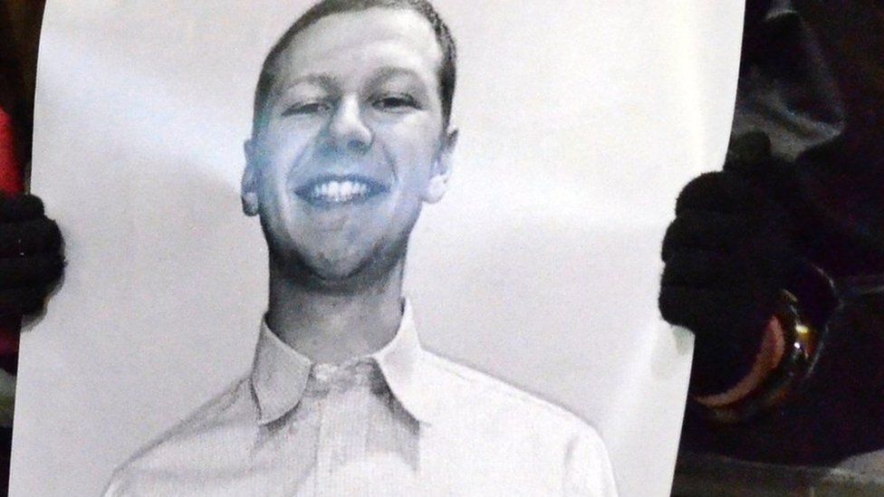 A protester holds a photo of Aaron Bushnell in Chicago.