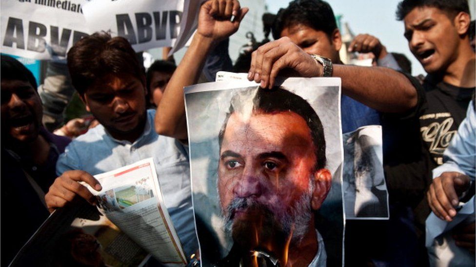 Protesters burn a photograph of Tarun Tejpal