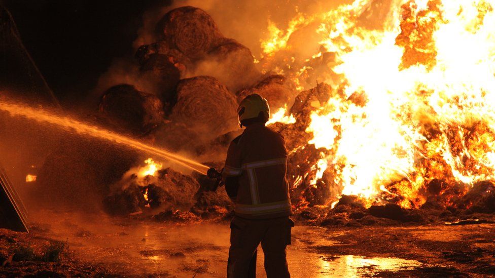 A firefighter attending a fire of hay bales