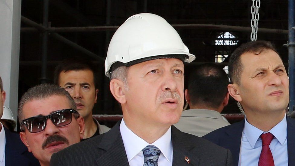 Turkish President Recep Tayyip Erdogan, wearing a construction hard hat, gazes into the middle distance squinting duringe of Ottoman Mosque in Ankara, Turkey on July 28, 2016