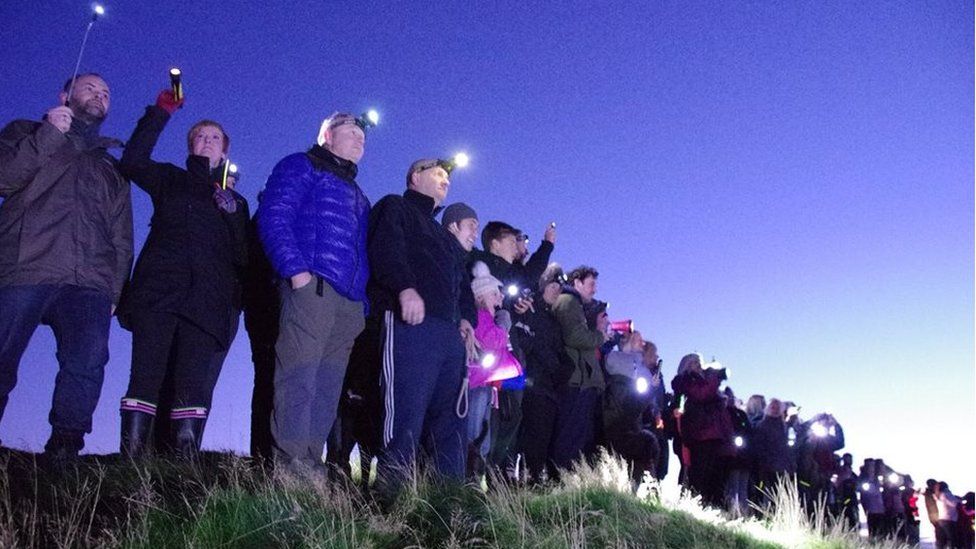 People hold torches atop Eston Nab