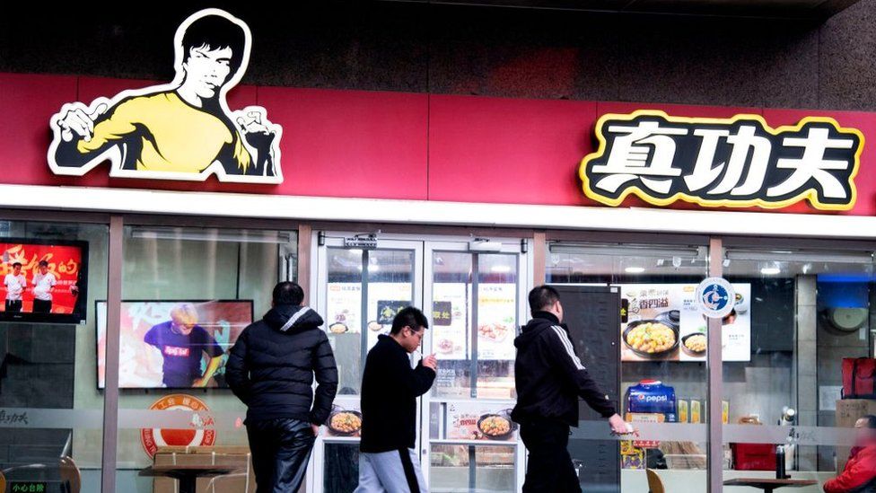 People walk past the restaurant Real Kung Fu, or Zhen Gongfu in Mandarin, run by fast food chain Kungfu Catering Management, in Beijing.