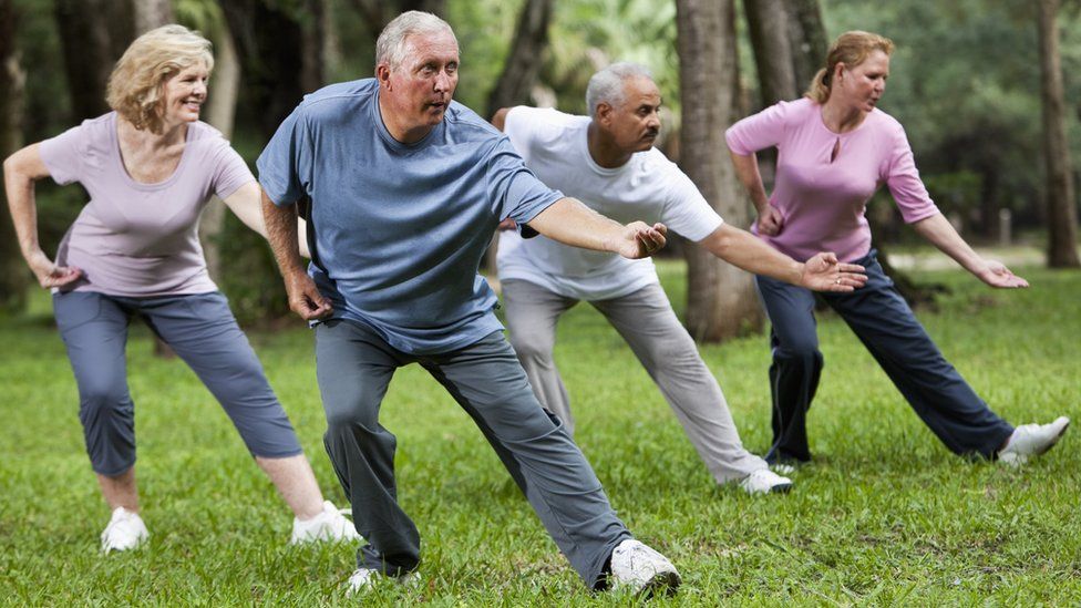 Adults practising tai chi in a park