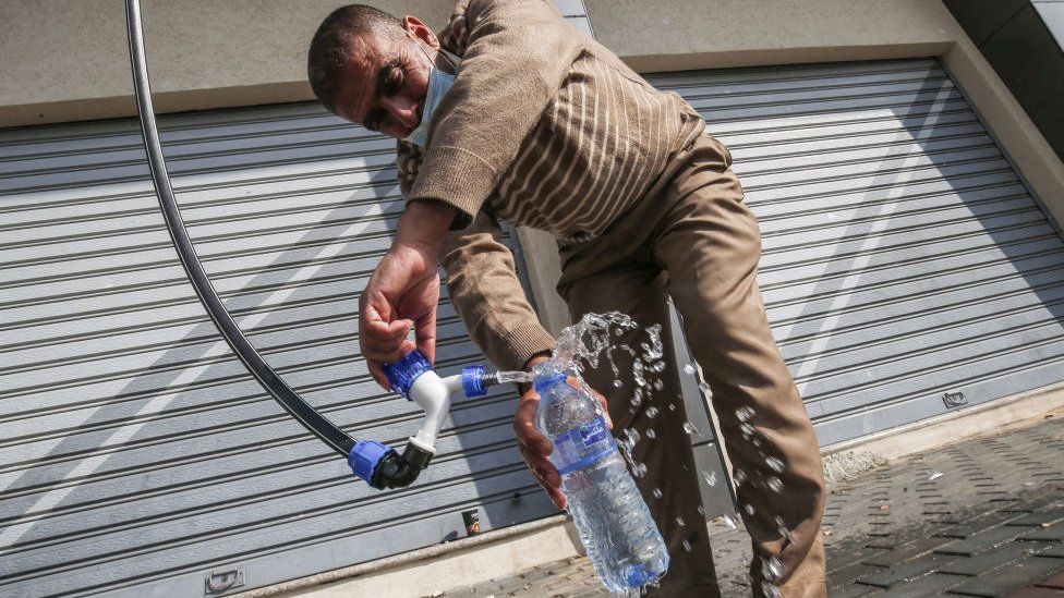Мужчина наливает воду в пластиковую бутылку