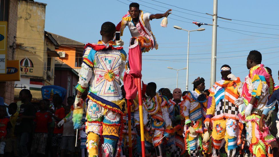 Man on stilts towers over other people on the parade in Sekondi Ghana