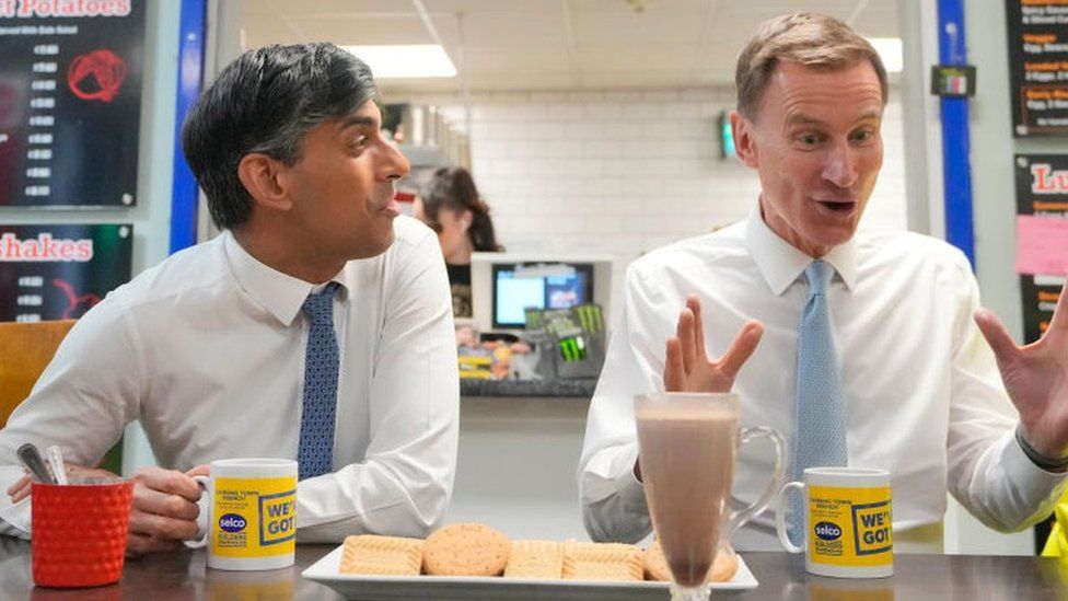Prime Minister Rishi Sunak (L) and Chancellor Jeremy Hunt (R) have tea and biscuits on a post-Budget visit