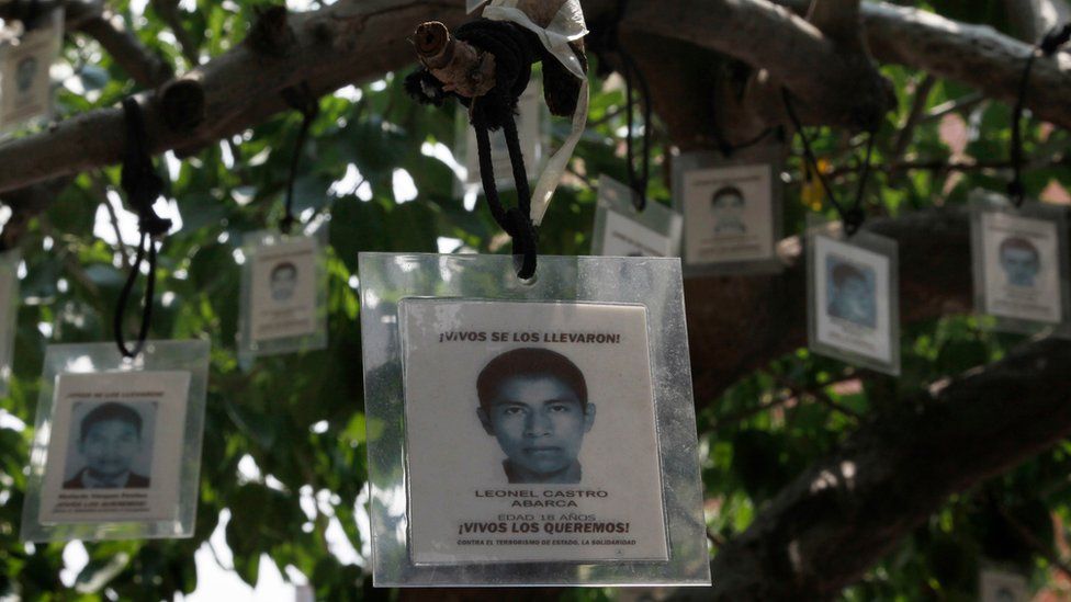 Laminated images of the 43 missing students from the Isidro Burgos rural teachers college hang from a tree in Mexico City, Friday, Aug. 26, 2016.