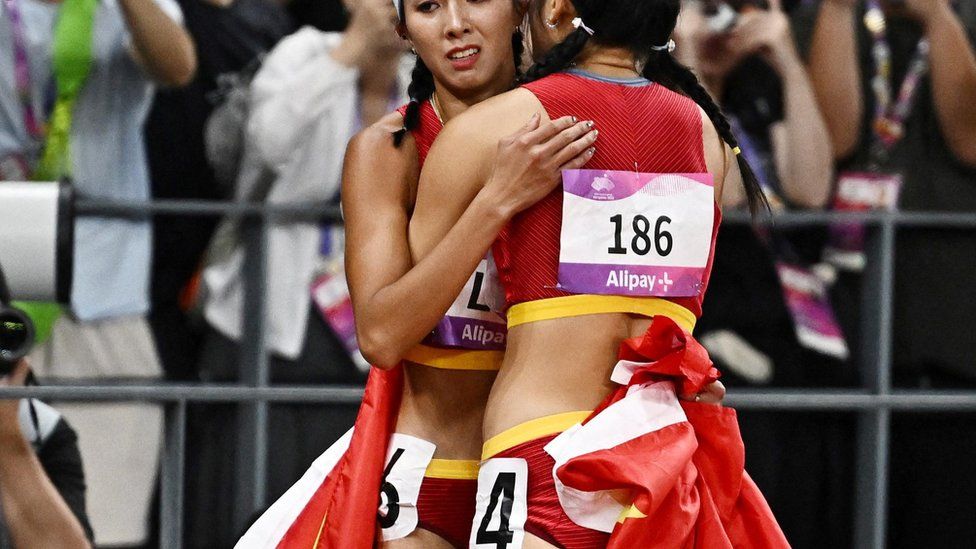 China's Yanni Wu and China's Yuwei Lin embrace after the women's 100m hurdles
