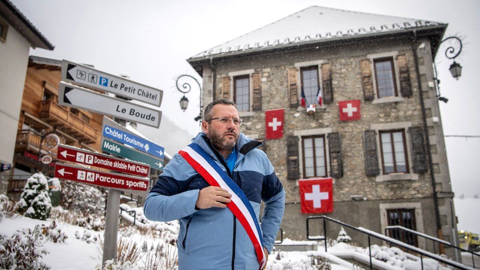 Nicolas Rubin, the Mayor of Châtel, poses with a scarf in the colours of France in front of the Town Hall