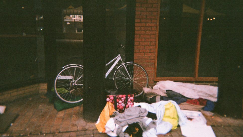 A bike, bags and bedding on the street outside a building