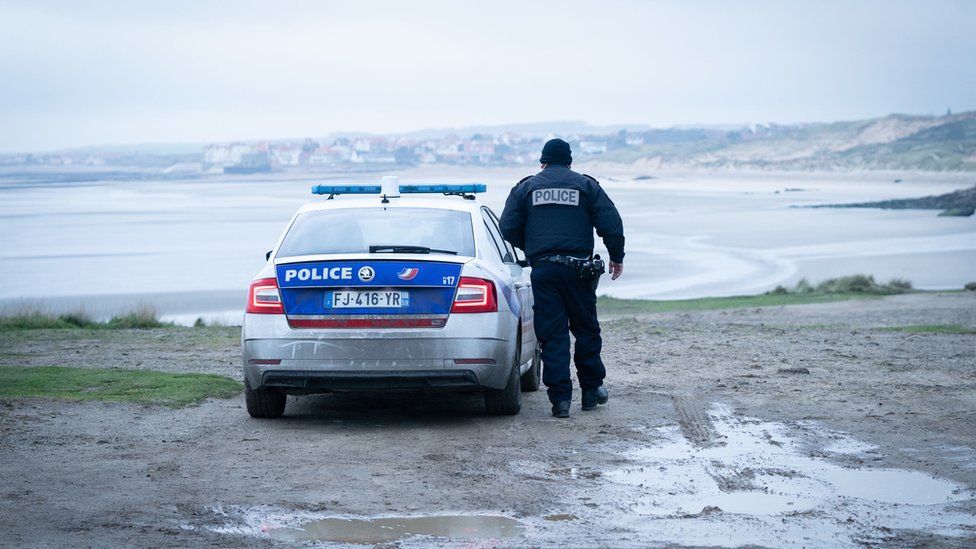 French police look out over a beach near Wimereux in France